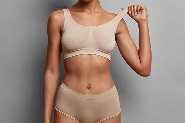 Mid body shot of a female model wearing nude colored undergarments