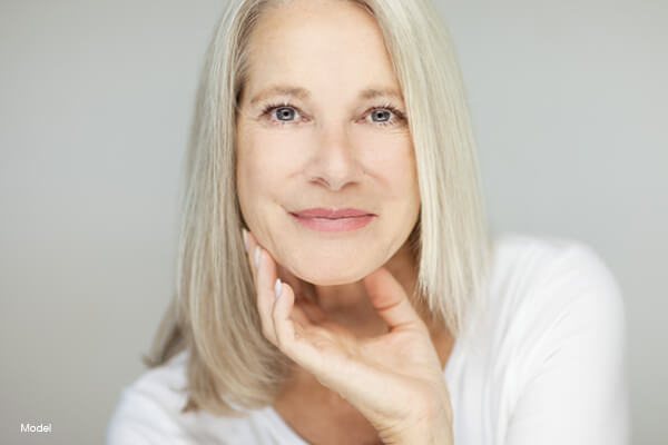 Headshot of a middle aged female model resting her chin in her hand