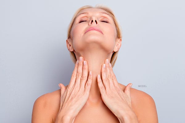 Middle aged female model rubbing her smooth neck