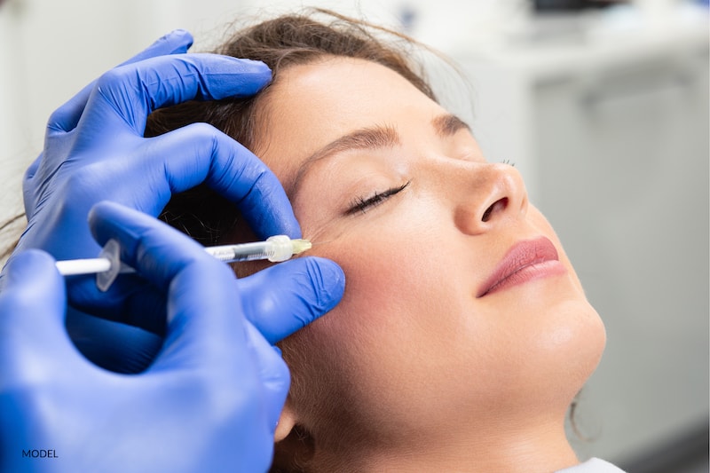 woman getting an injection to treat her crow's feet around her eyes.