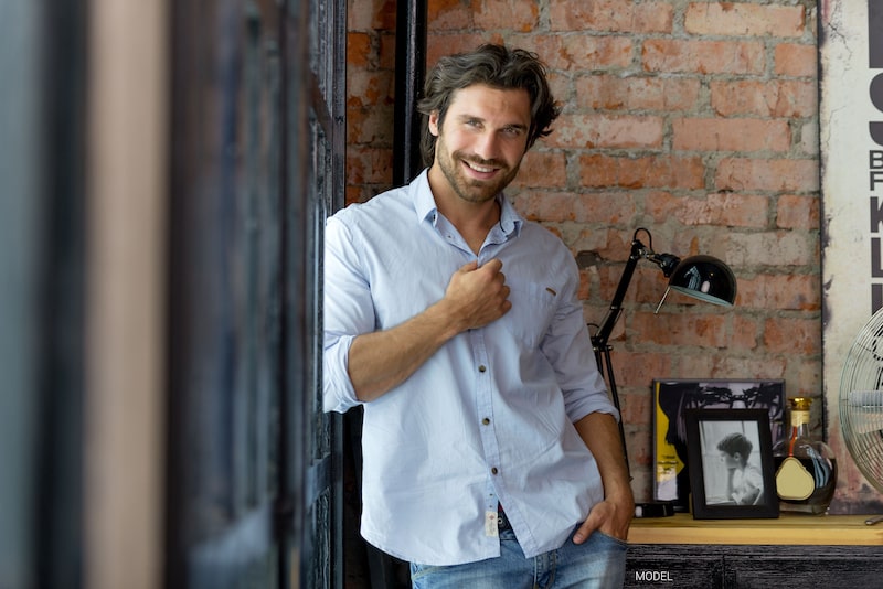 Handsome man leaning against a wall and smiling