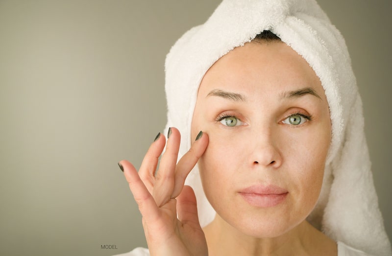 Beautiful middle-aged woman looking at the camera while touching her face with a finger.